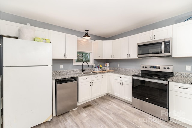 kitchen featuring light wood-type flooring, white cabinets, visible vents, appliances with stainless steel finishes, and a sink