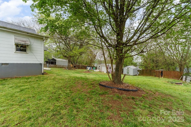 view of yard with a storage shed, fence, and an outbuilding