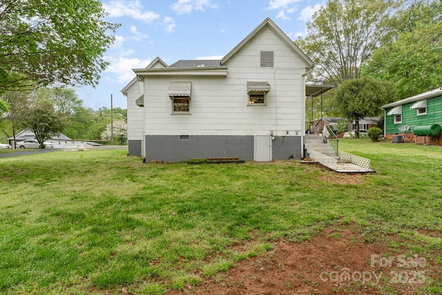 back of house with a yard, central AC, heating fuel, and roof with shingles