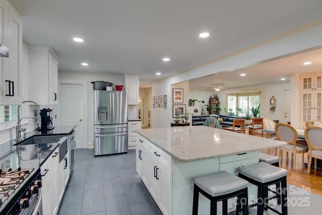 1473 12th Street Dr NW, Hickory, NC 28601 - kitchen featuring a kitchen island, a kitchen bar, a sink, light stone counters, and stainless steel appliances