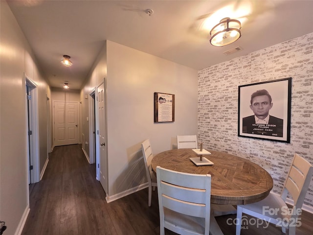 dining space with visible vents, baseboards, an accent wall, and wood finished floors