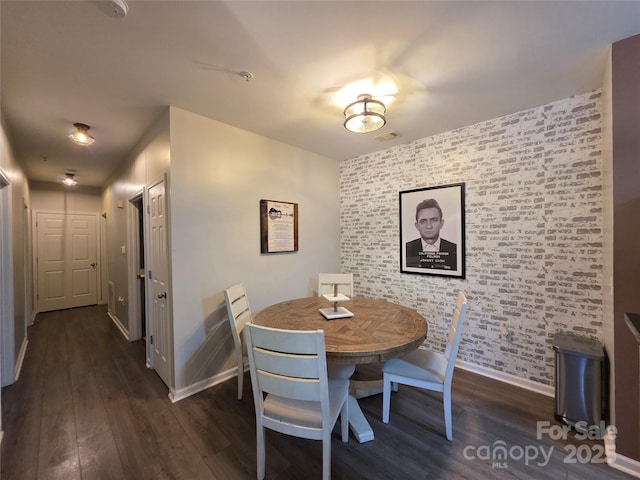 dining space with visible vents, baseboards, an accent wall, and wood finished floors