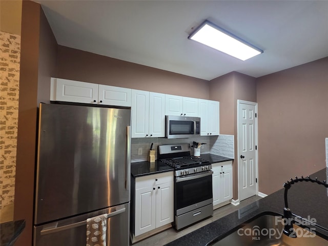 kitchen featuring decorative backsplash, white cabinets, and stainless steel appliances