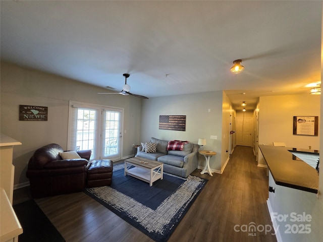 living area with dark wood-type flooring, baseboards, and a ceiling fan