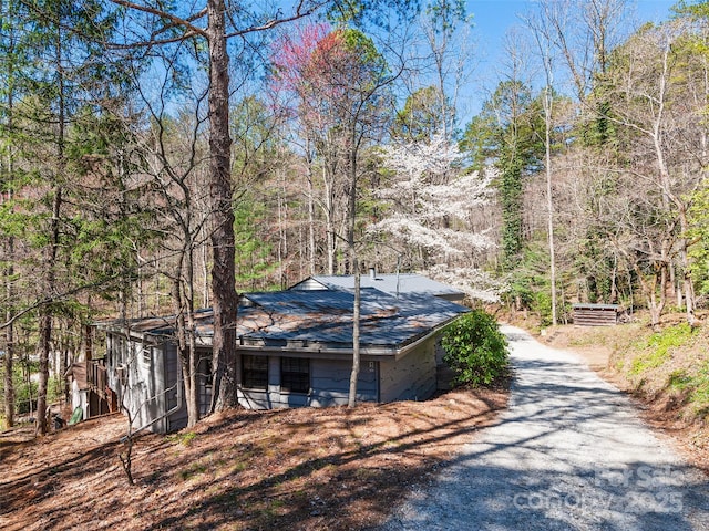 exterior space featuring a view of trees and gravel driveway