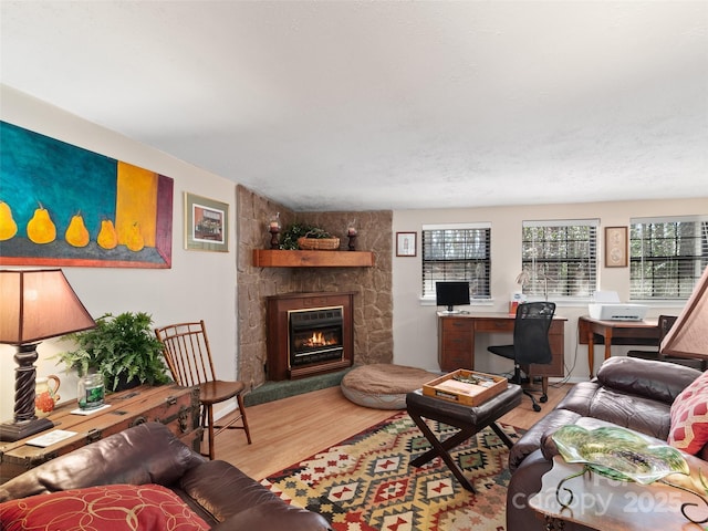 living room with a stone fireplace and wood finished floors