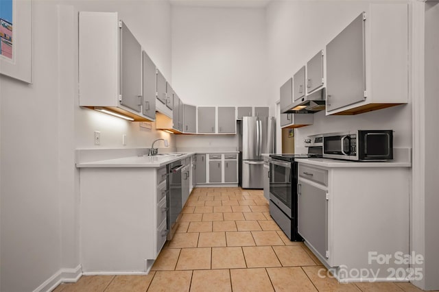 8 Hunting Country Trl, Tryon, NC 28782 - kitchen with light tile patterned floors, a high ceiling, light countertops, under cabinet range hood, and stainless steel appliances