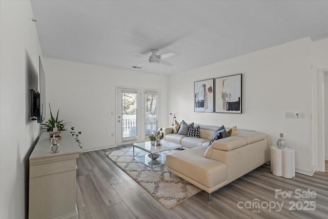 living room with visible vents, ceiling fan, wood finished floors, and baseboards