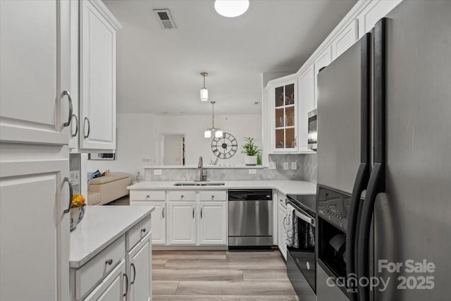 kitchen featuring white cabinets, a sink, light countertops, light wood-type flooring, and appliances with stainless steel finishes