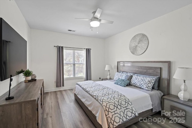 bedroom with visible vents, baseboards, a ceiling fan, and wood finished floors