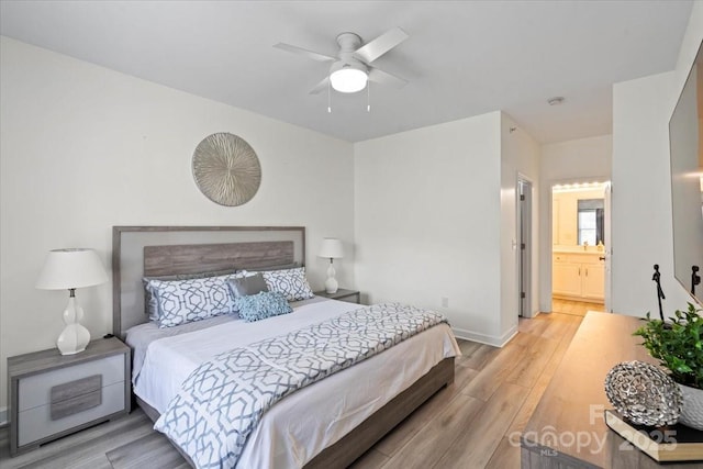 bedroom with ensuite bathroom, baseboards, a ceiling fan, and light wood-style floors