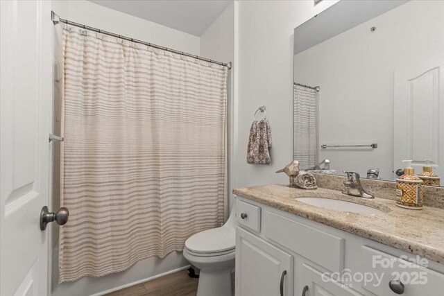 bathroom with toilet, wood finished floors, vanity, and shower / bath combo with shower curtain