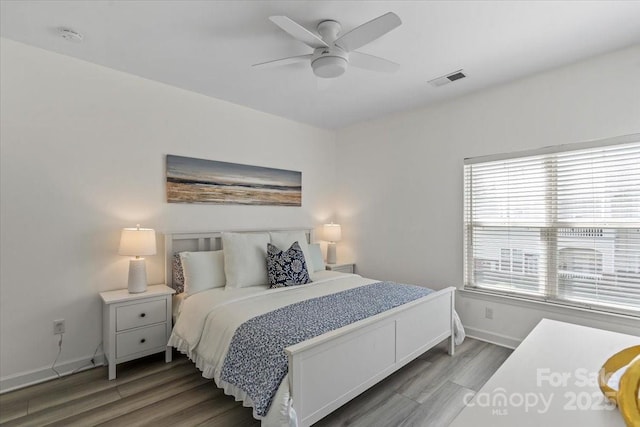 bedroom featuring wood finished floors, baseboards, a ceiling fan, and visible vents