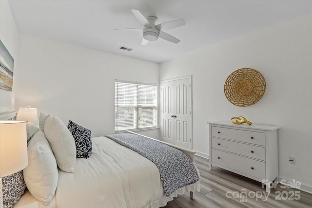 bedroom with visible vents, a closet, baseboards, and wood finished floors