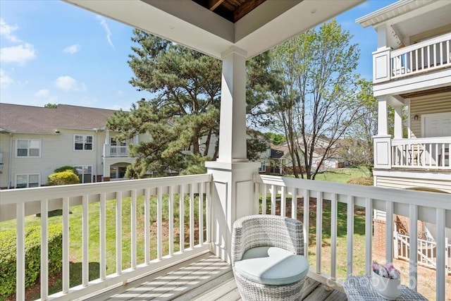 wooden deck featuring a yard, a residential view, and covered porch