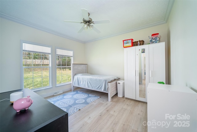 bedroom featuring a ceiling fan, crown molding, visible vents, and light wood-style flooring