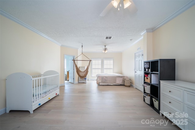 bedroom with light wood-type flooring, a textured ceiling, crown molding, and baseboards