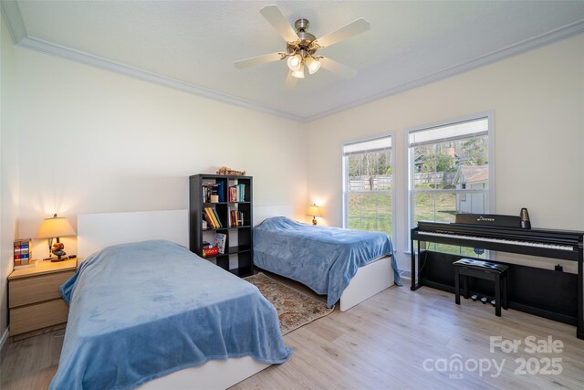 bedroom with wood finished floors, crown molding, and ceiling fan
