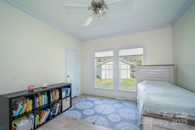 bedroom featuring baseboards, wood finished floors, visible vents, and ornamental molding