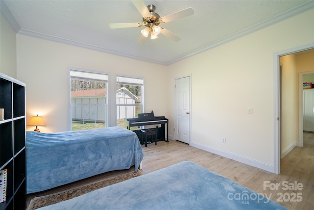 bedroom featuring wood finished floors, crown molding, baseboards, and a ceiling fan