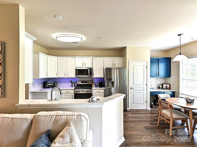 kitchen featuring appliances with stainless steel finishes, backsplash, light countertops, blue cabinets, and dark wood finished floors