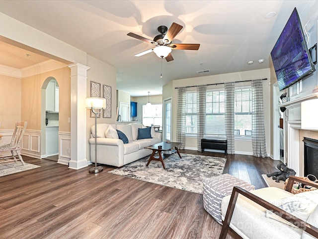 living room with wood finished floors, arched walkways, a fireplace, visible vents, and a ceiling fan
