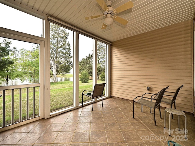 unfurnished sunroom with ceiling fan, a healthy amount of sunlight, and a water view