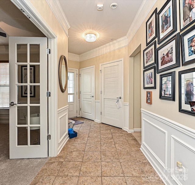 doorway to outside with a wainscoted wall, crown molding, and a decorative wall
