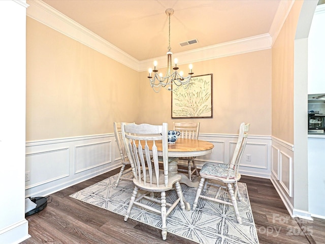 dining room featuring visible vents, wood finished floors, a notable chandelier, and crown molding