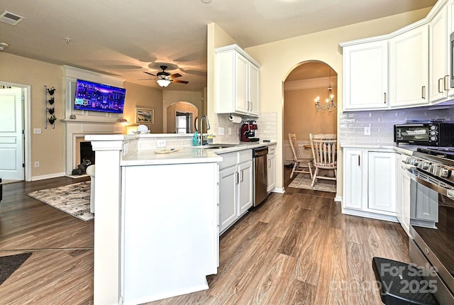 kitchen with a sink, stainless steel appliances, visible vents, arched walkways, and ceiling fan with notable chandelier