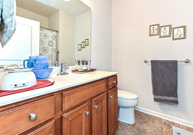 bathroom with toilet, vanity, and baseboards