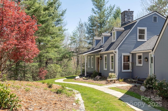 exterior space with a shingled roof and a chimney