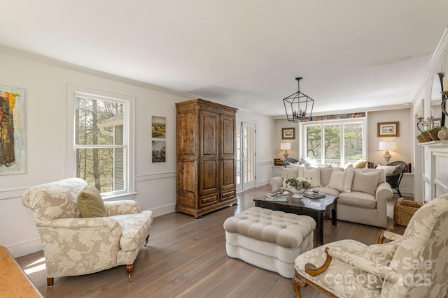 living room featuring ornamental molding, baseboards, light wood-type flooring, and a chandelier