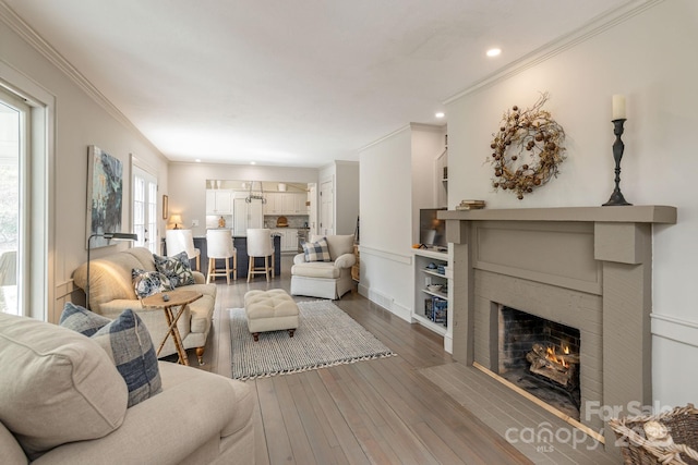 living room featuring crown molding, wood-type flooring, recessed lighting, and a fireplace