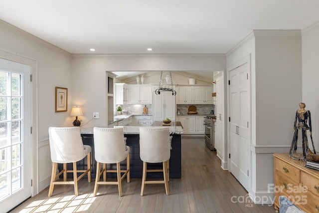 dining room with a decorative wall, ornamental molding, hardwood / wood-style flooring, recessed lighting, and a wainscoted wall