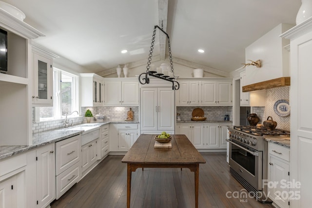 kitchen featuring white cabinets, stainless steel range, and lofted ceiling