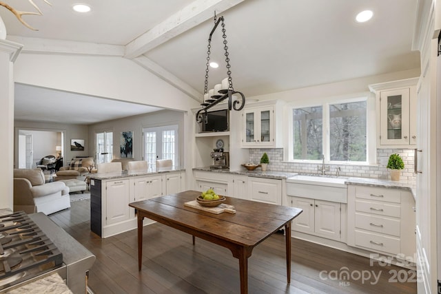 kitchen with lofted ceiling with beams, dark wood-style floors, glass insert cabinets, white cabinets, and a sink