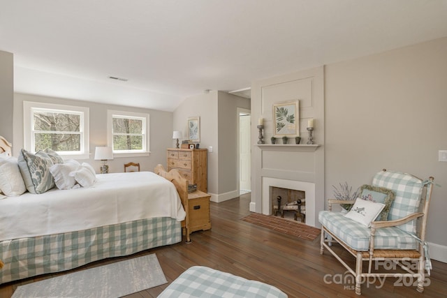 bedroom with baseboards, a fireplace, vaulted ceiling, and hardwood / wood-style flooring