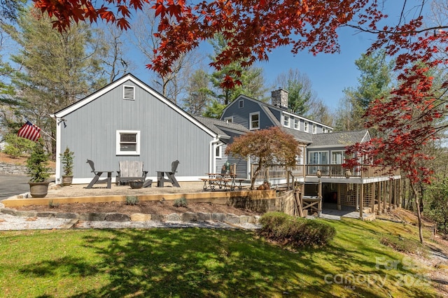 back of house with a patio, a yard, a deck, and a chimney