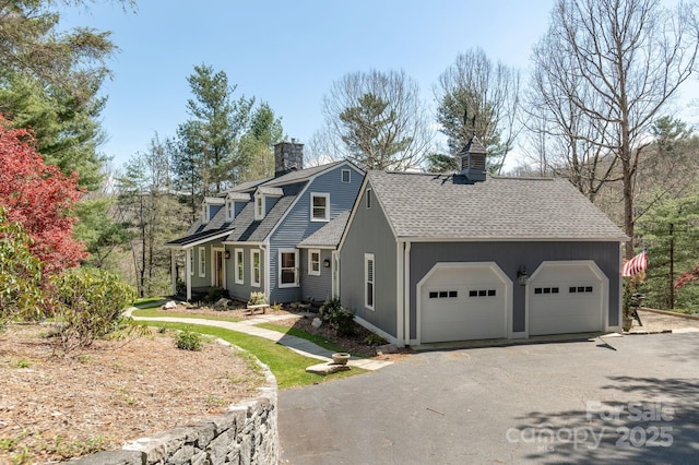 view of front of property with a gambrel roof, a garage, roof with shingles, a chimney, and driveway