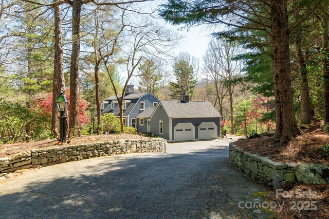 view of property exterior with a garage, aphalt driveway, and a chimney