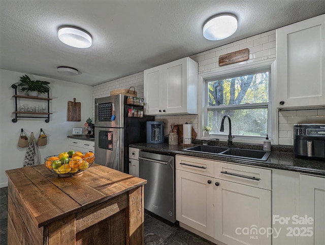 317 Balsam Dr, Waynesville, NC 28786 - kitchen featuring a textured ceiling, backsplash, dark countertops, stainless steel appliances, and a sink