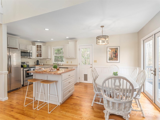 kitchen with a wealth of natural light, light wood finished floors, a kitchen breakfast bar, and stainless steel appliances