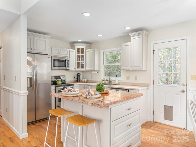 kitchen featuring recessed lighting, a kitchen island, light wood-style floors, stainless steel appliances, and a sink