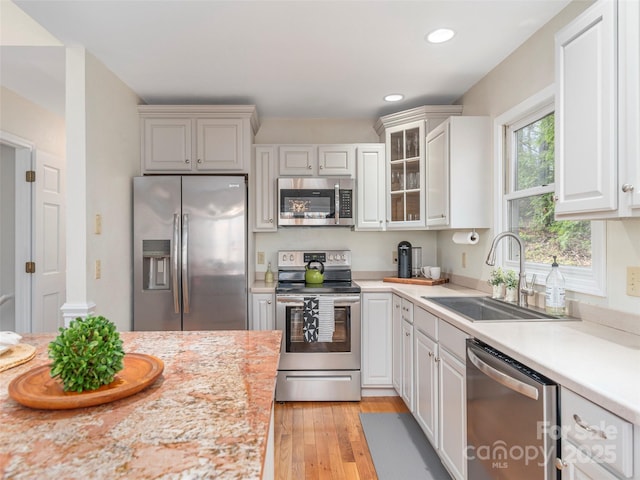 kitchen with a sink, light countertops, light wood-type flooring, and stainless steel appliances
