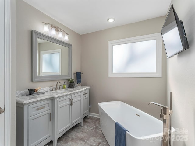 full bath featuring a freestanding tub, vanity, and a wealth of natural light