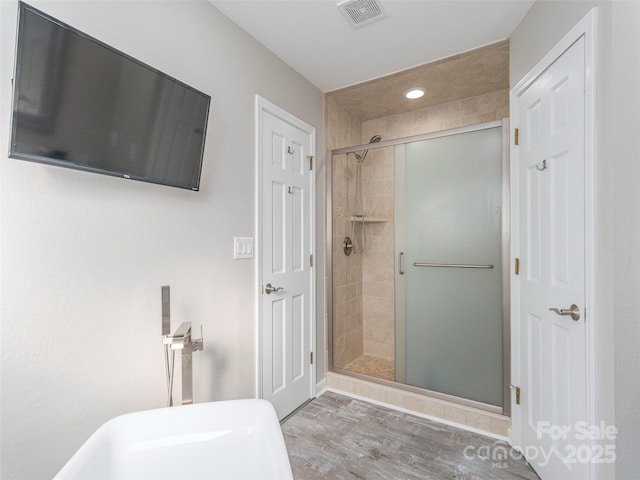 bathroom with a shower stall, wood finished floors, and visible vents