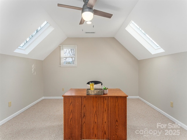 office featuring light carpet, vaulted ceiling with skylight, and baseboards