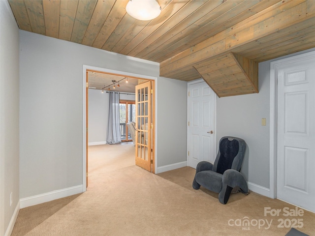 living area featuring carpet flooring, baseboards, wooden ceiling, and track lighting