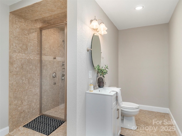 bathroom with a tile shower, vanity, baseboards, and toilet
